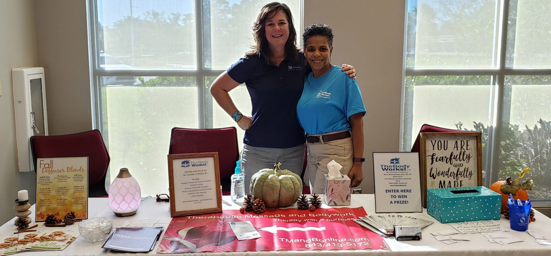 Two women standing in front of a table with items on it.