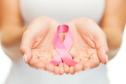 A woman's hands holding a pink breast ribbon.