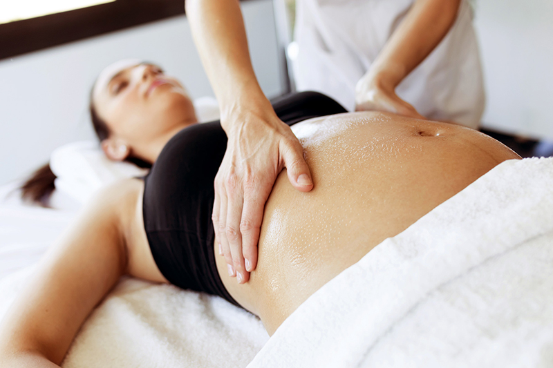 A pregnant woman is being massaged by a massage therapist.