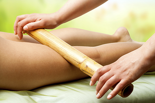 A woman getting a massage with a bamboo stick.
