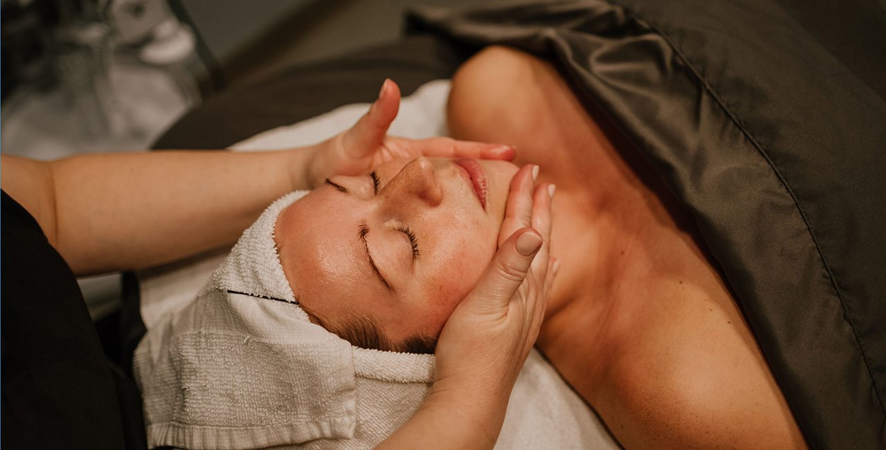 A woman getting a facial massage at a spa.