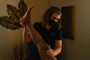 A woman giving a massage to a man's leg.