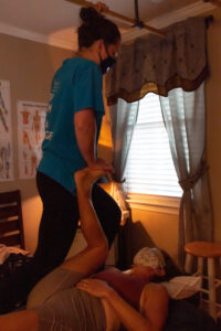 A woman is being helped by a massage therapist in a room.