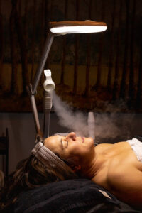 A woman laying on a bed with a steam machine.
