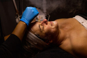 A woman is getting a steam treatment on her face.