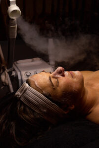 A woman is getting a facial treatment with a steam machine.
