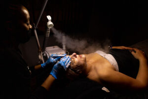 A woman getting a facial treatment in a dark room.