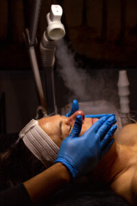 A woman getting a facial treatment with a steam machine.