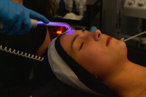 A woman getting a facial treatment with a blue light.