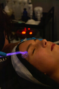 A woman getting a facial treatment with a blue light.