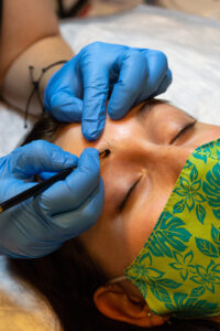 A woman is getting her eyebrows tattooed.