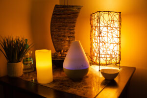 A table with a lamp, a candle, and a diffuser.