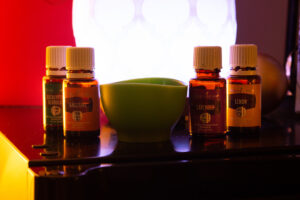A group of essential oils on a table next to a lamp.